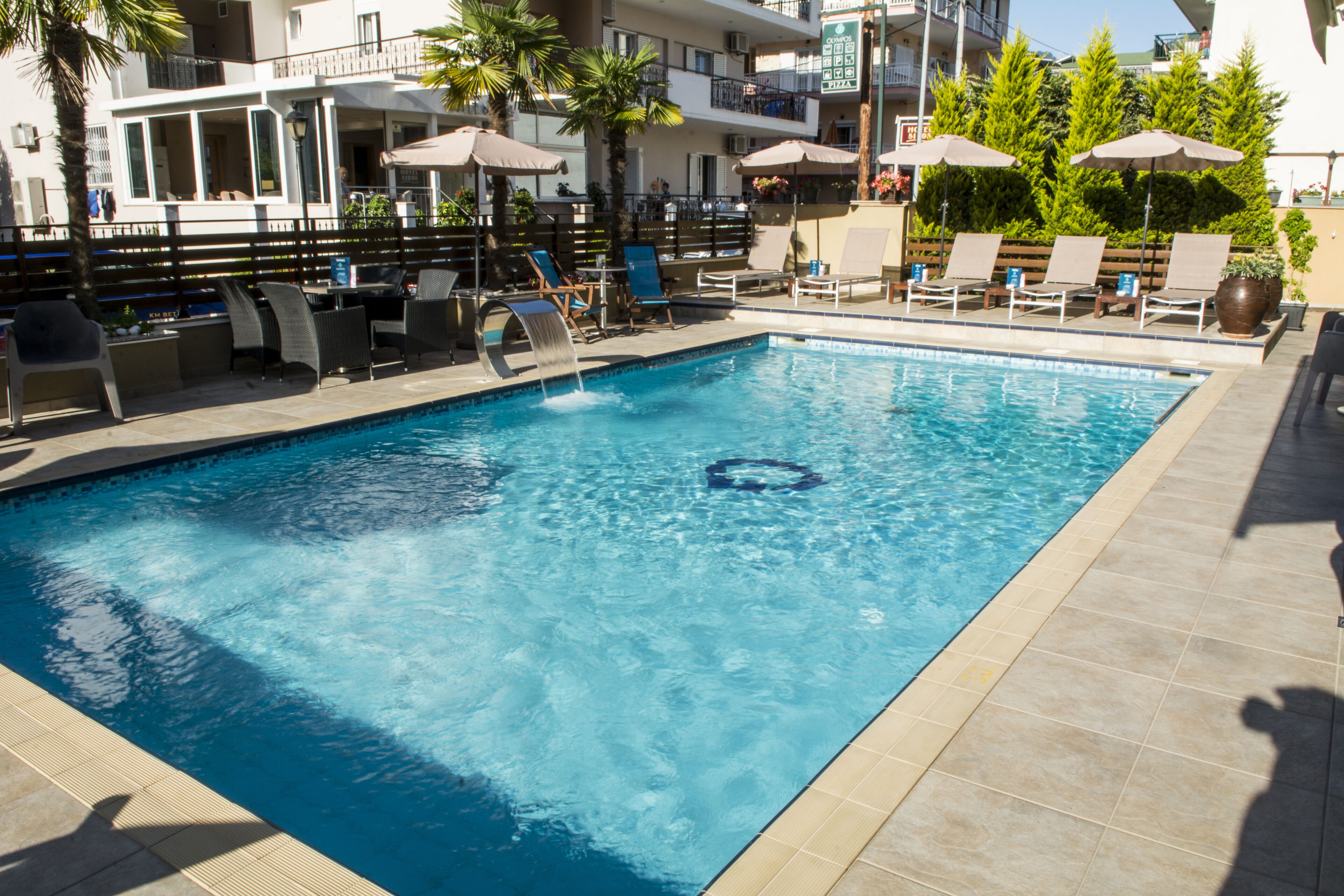 Una piscina al aire libre, sombrillas, sillones reclinables de piscina