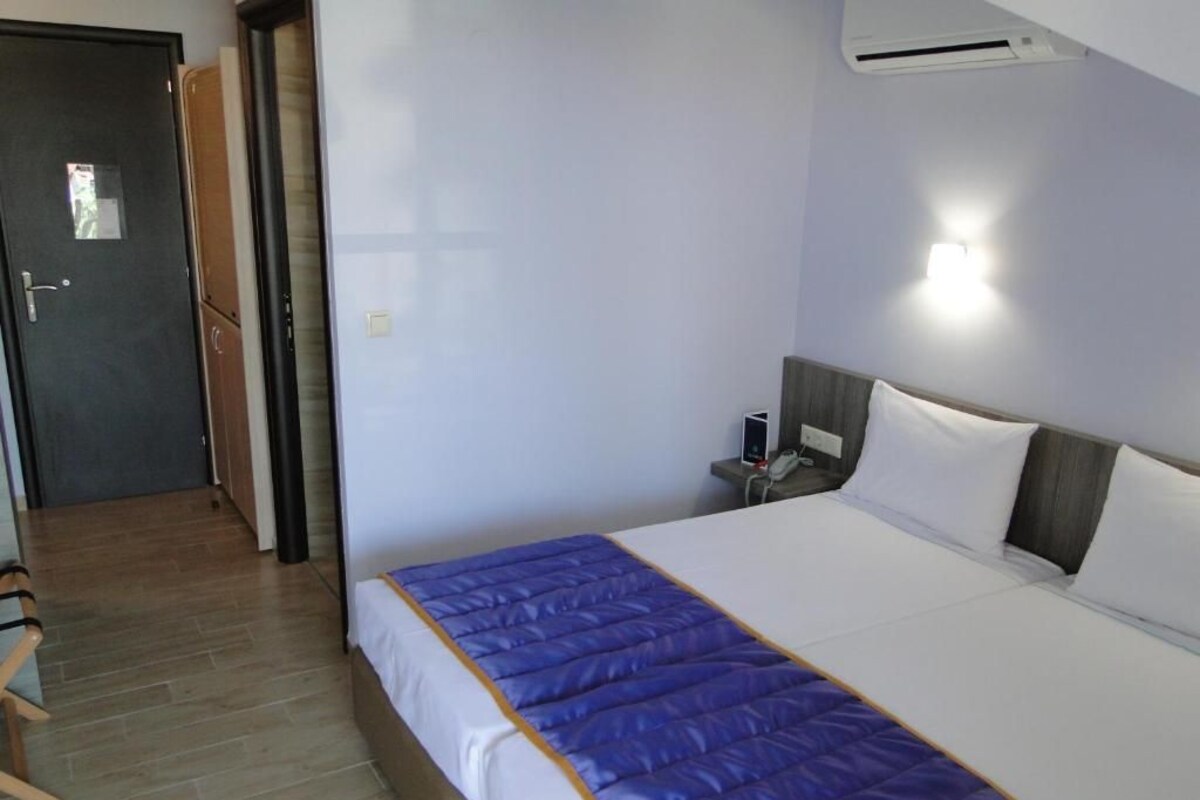 A hotel room with a bed, a bedside table, a chair, and a door.