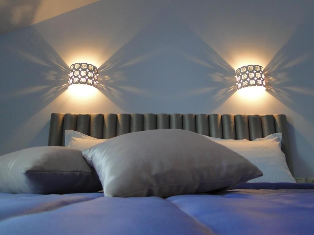 Ein Bett mit Kopfteil, zwei Wandleuchten und Kissen.