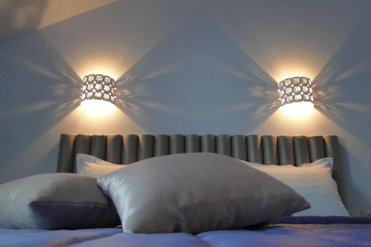 Ein Bett mit Kopfteil, zwei Wandleuchten und Kissen.