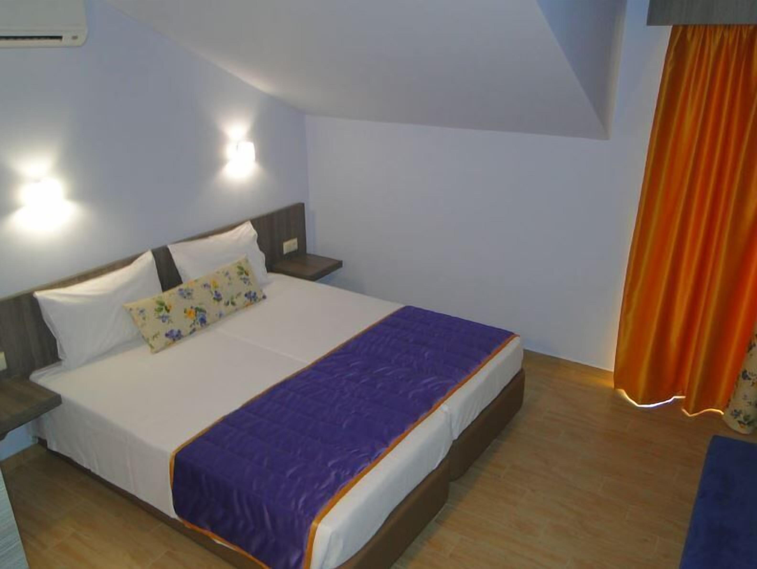 Une chambre à coucher avec un lit, des tables de chevet et un luminaire fixé au mur.