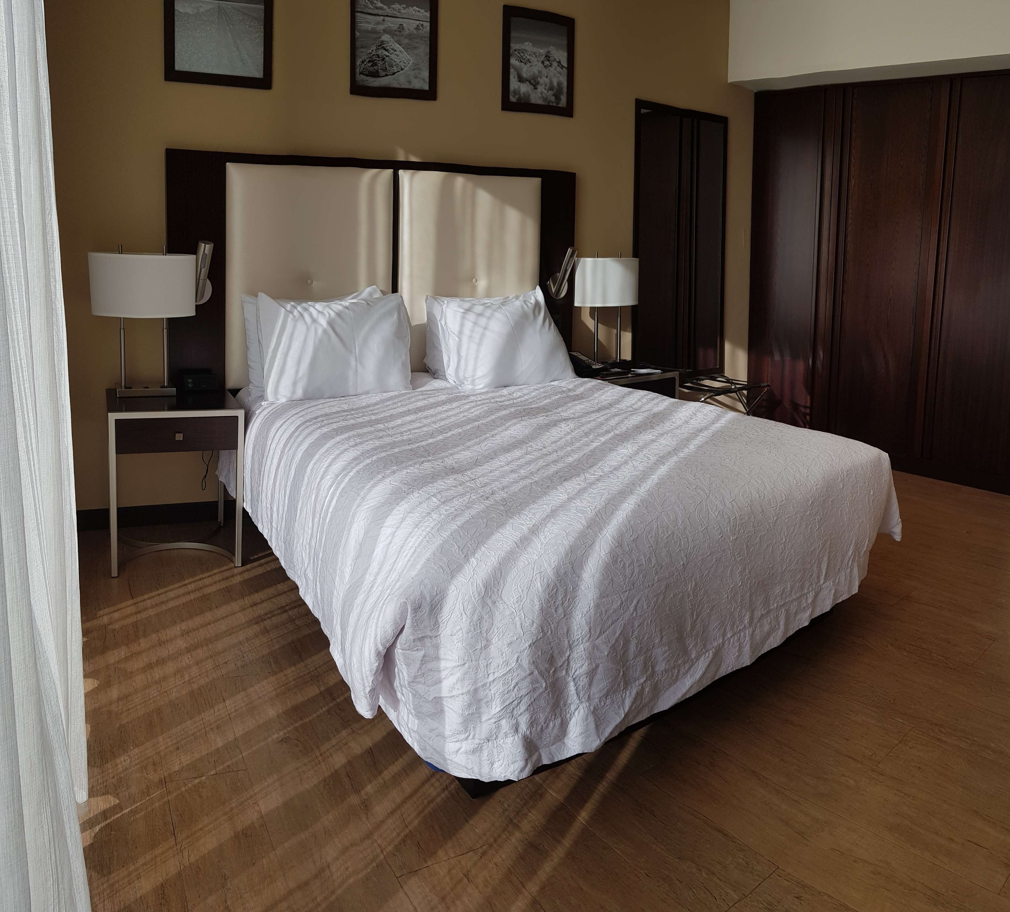 A neatly made bed with a white bedspread in a hotel room.