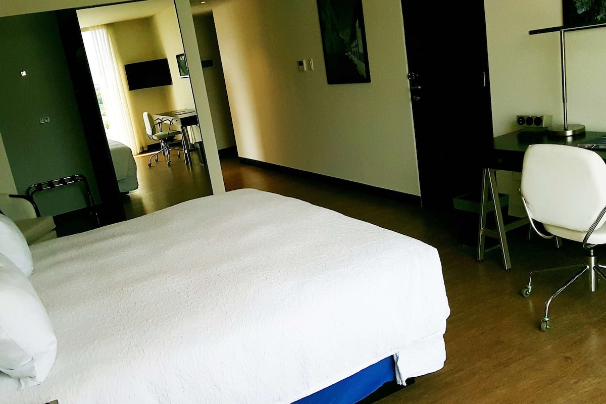 Ein Hotelzimmer mit einem großen Bett, einem Schreibtisch und einem Stuhl.
