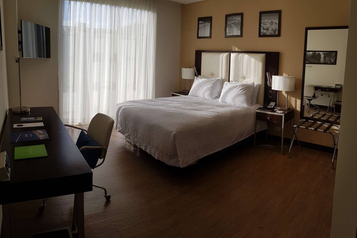 Ein Hotelzimmer mit Bett, Schreibtisch, Stuhl und einer Schreibtischlampe.