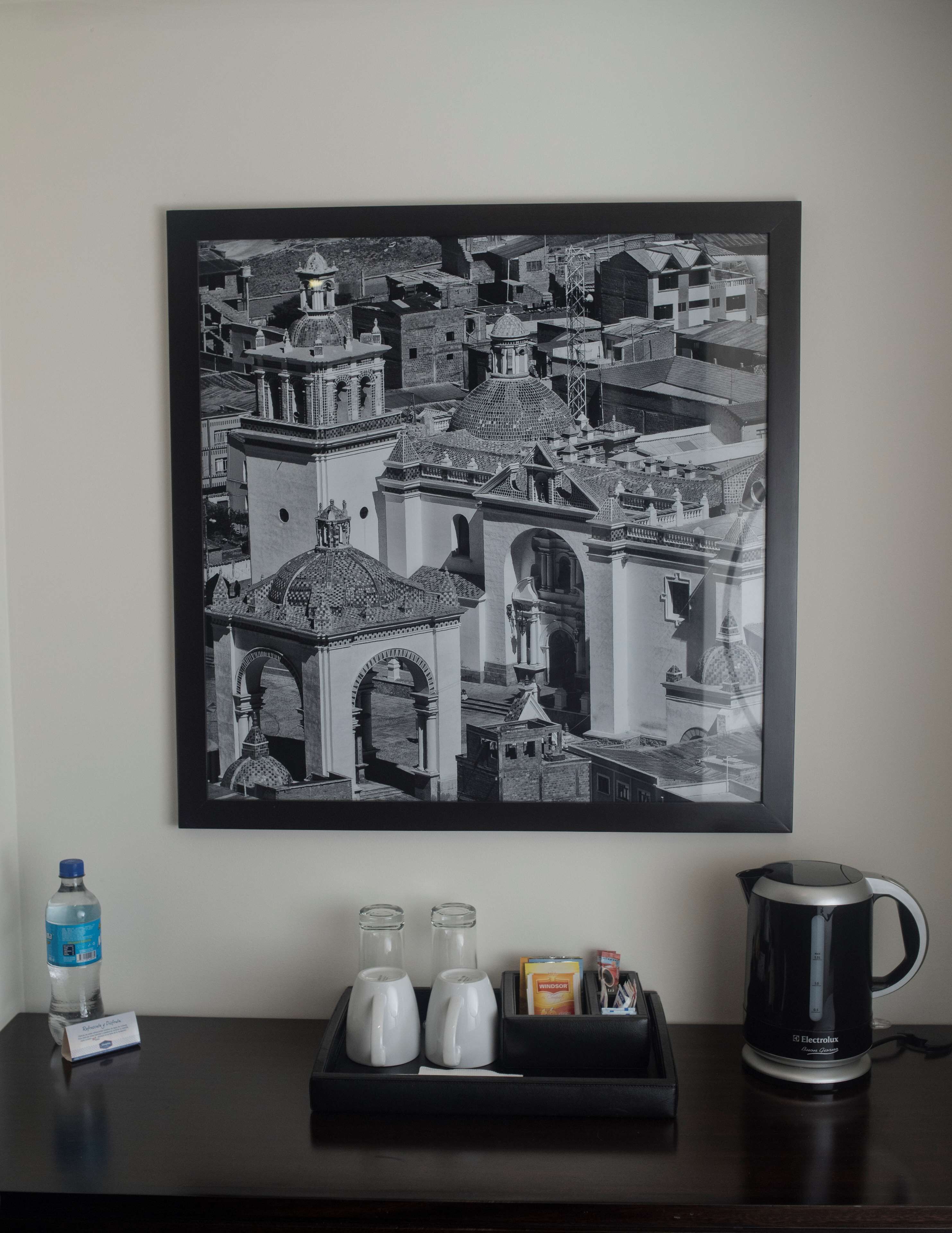 A framed black and white photograph of a cityscape with a coffee maker and a water bottle on a table.