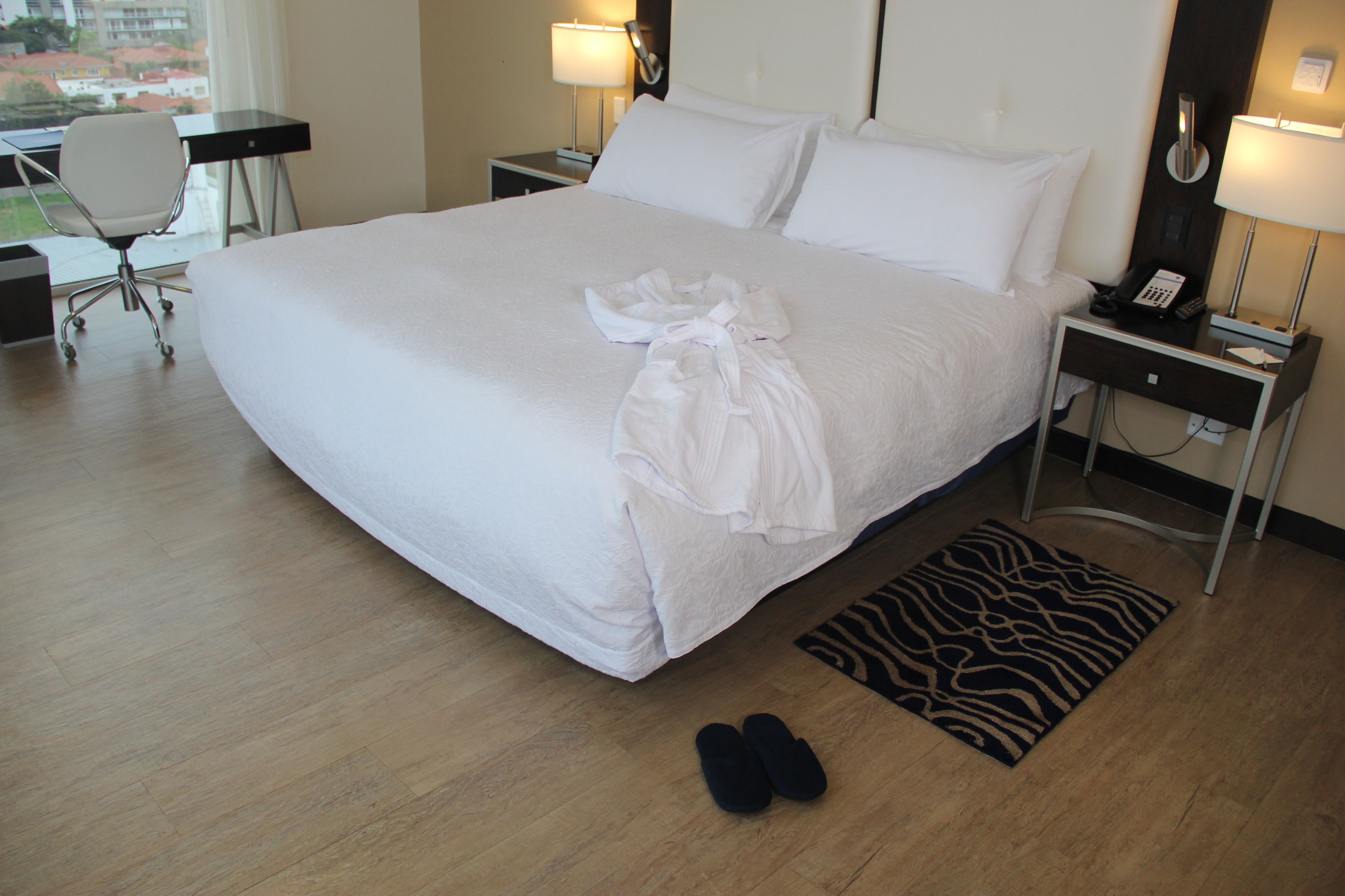 Une chambre d’hôtel avec un grand lit, un bureau, une chaise et une vue sur la ville.