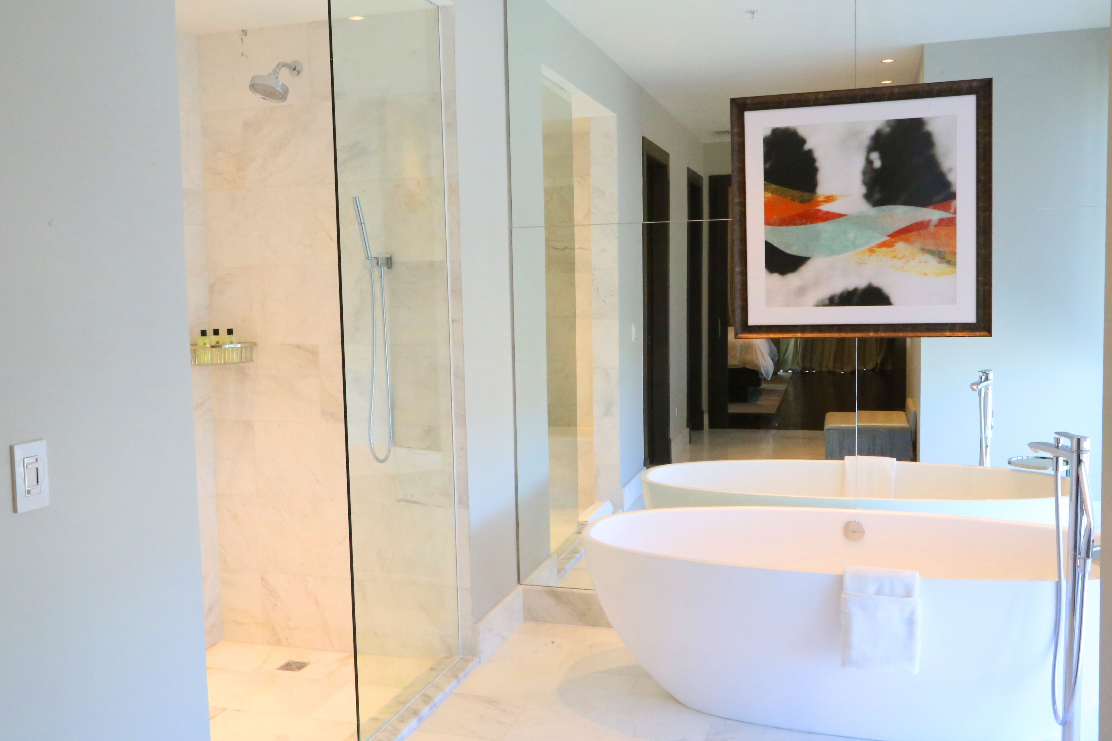 A modern bathroom with a glass-enclosed shower, a freestanding bathtub, and a large mirror.