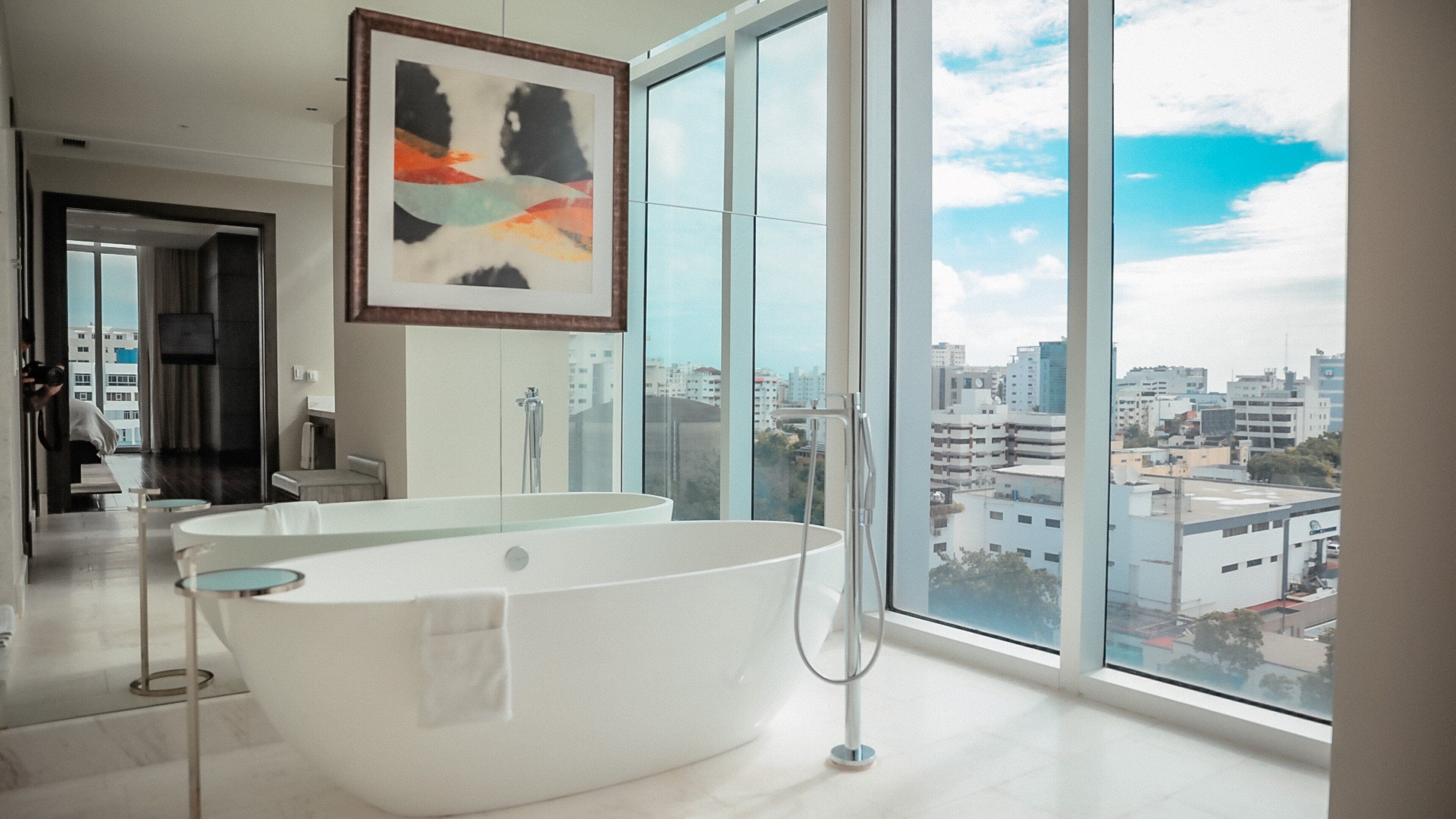 Un baño moderno con una bañera independiente, ventanas amplias que ofrecen vista a la ciudad y un diseño minimalista.