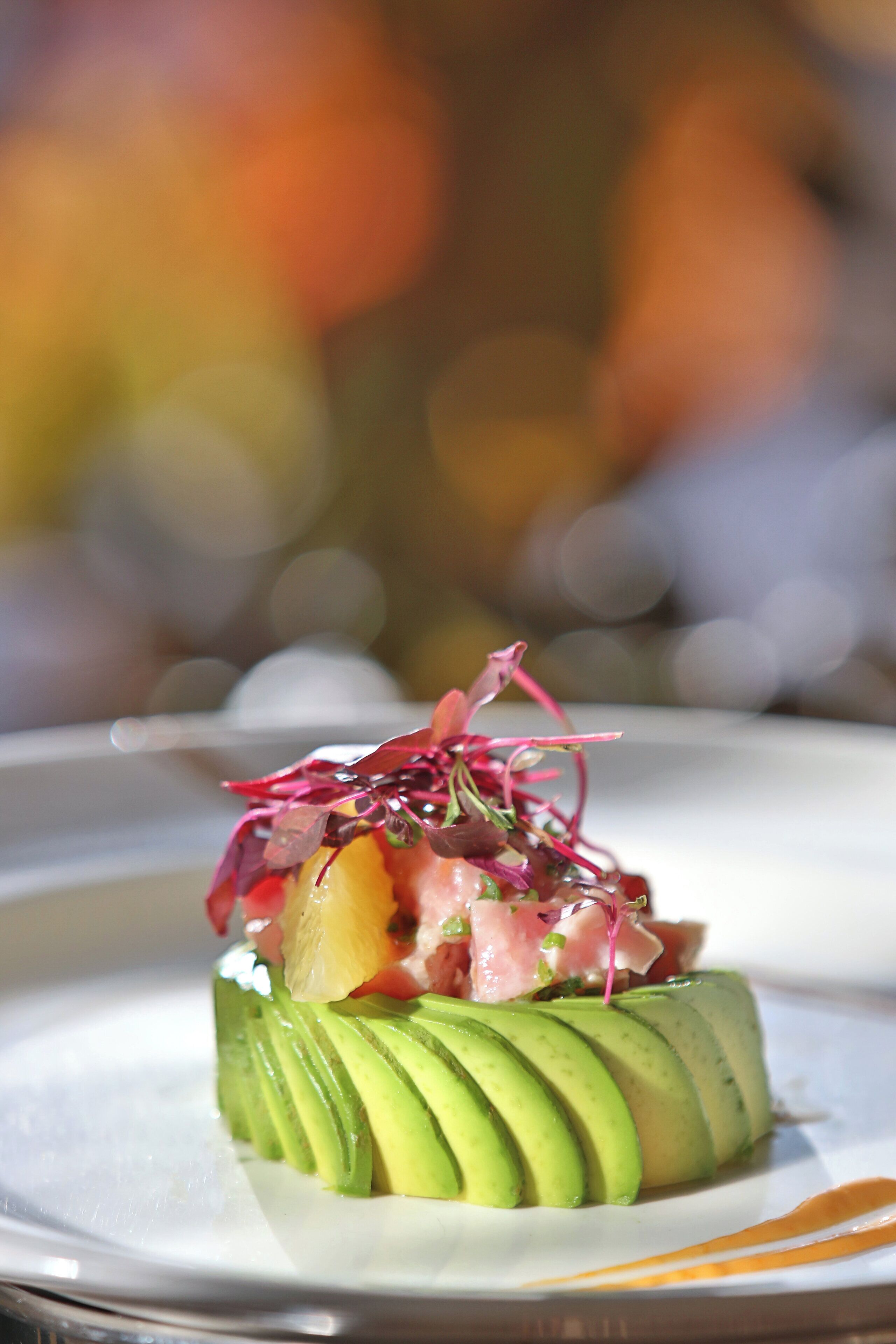 A plated dish with avocado slices, a pinkish topping, and a garnish.