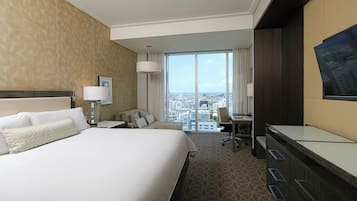 Une chambre d’hôtel avec un grand lit, un bureau, une chaise et un téléviseur fixé au mur.
