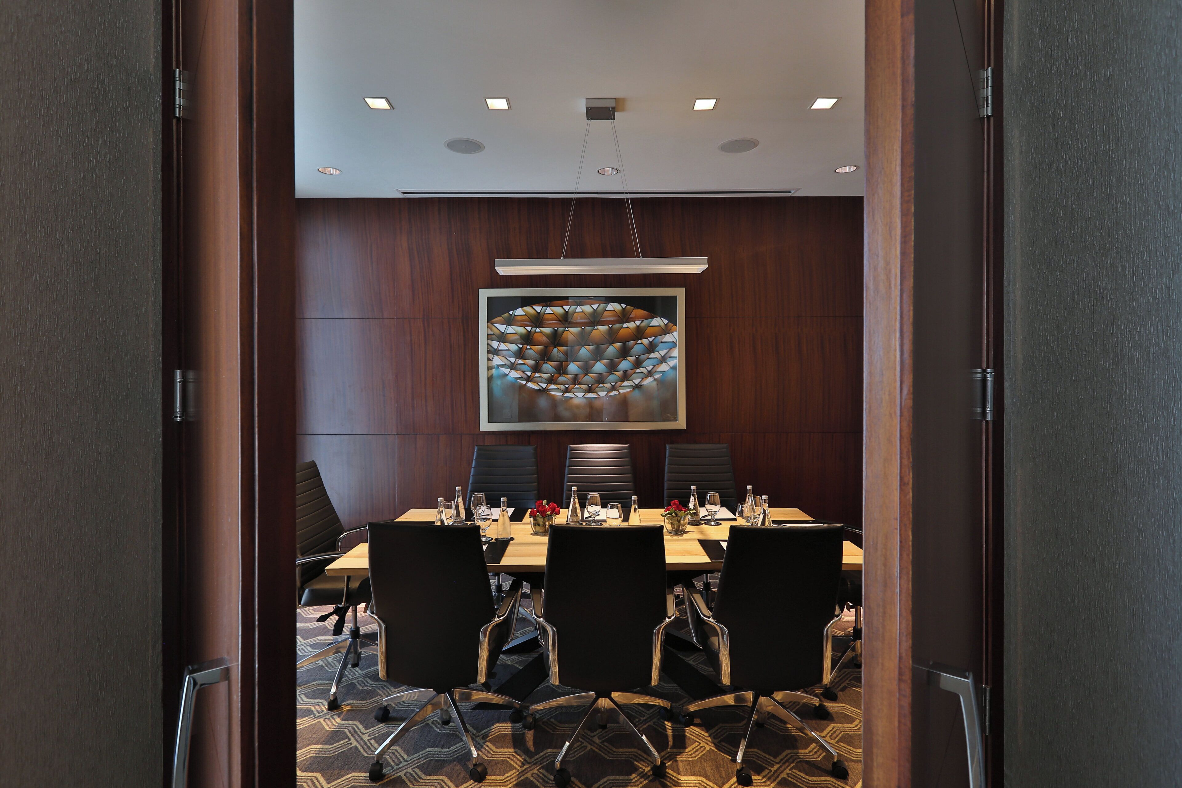 A conference room with a long table, chairs, and a large abstract painting on the wall.