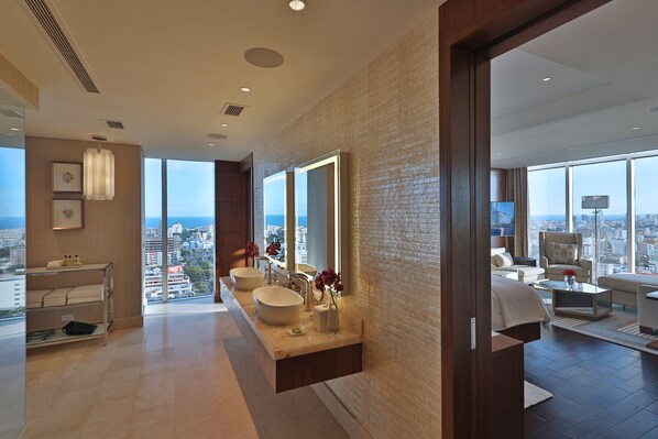 A modern bathroom with a large window, a vanity with two sinks, and a view of the city.