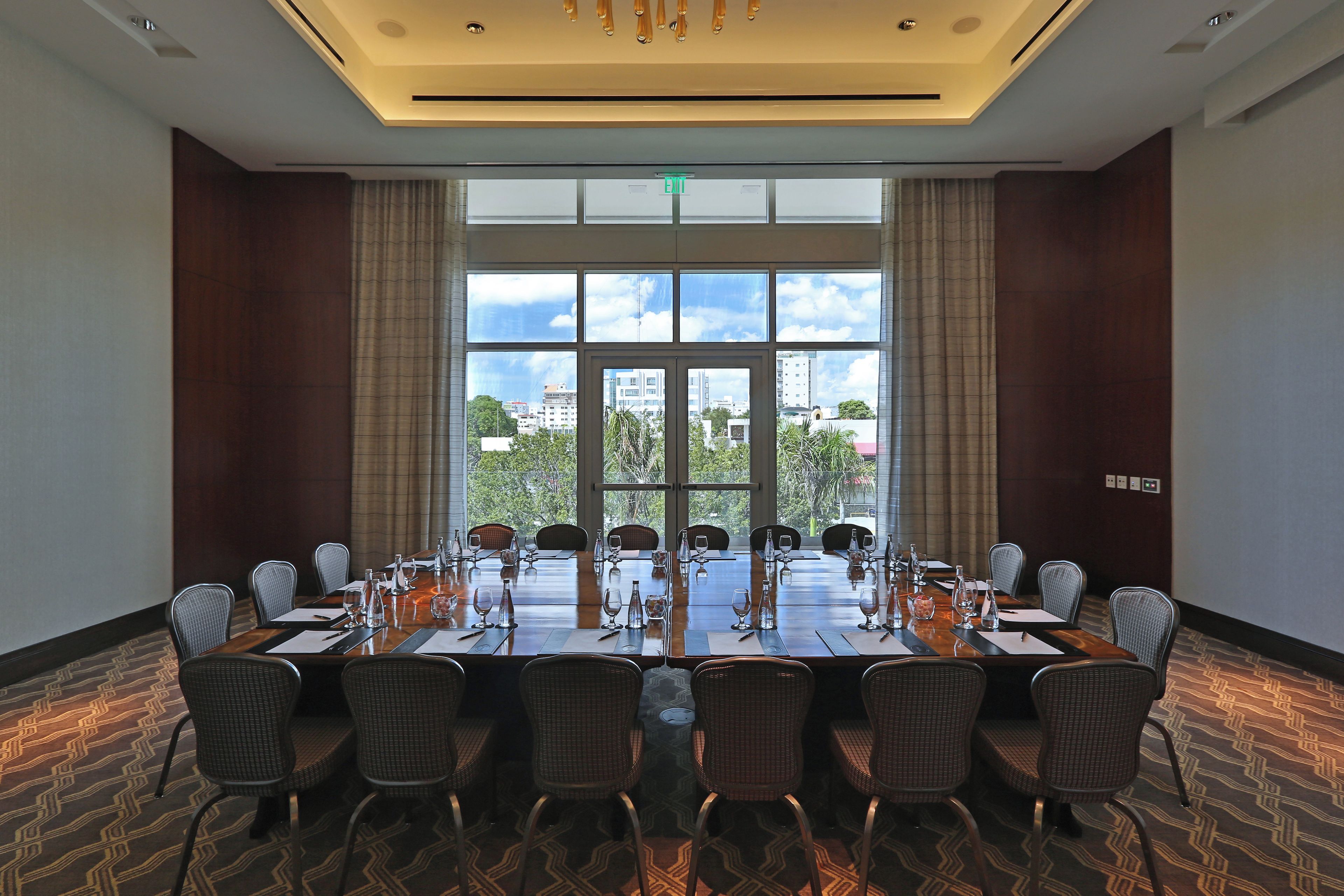 A conference room with a long table, chairs, and a view of the city through large windows.