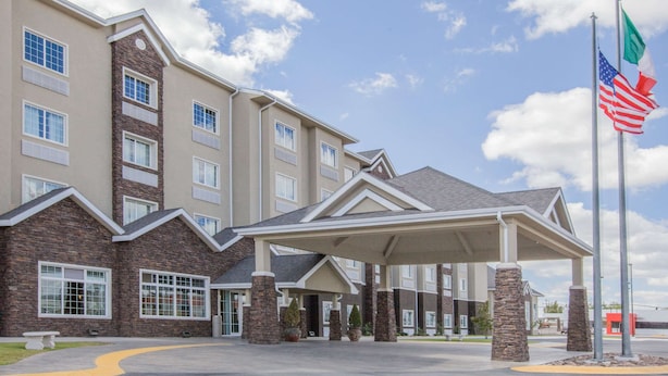 Ein mehrstöckiges Hotel mit überdachter Eingangspartei, einer Fassade aus Stein und den Flaggen der USA und Italiens.