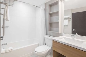A modern bathroom with a bathtub, toilet, and vanity with a mirror.