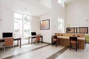 A modern hotel room with a desk, chairs, a large window, and a view of the outdoors. - Holiday Inn Express & Suites Boynton Beach West by IHG (Boynton Beach)