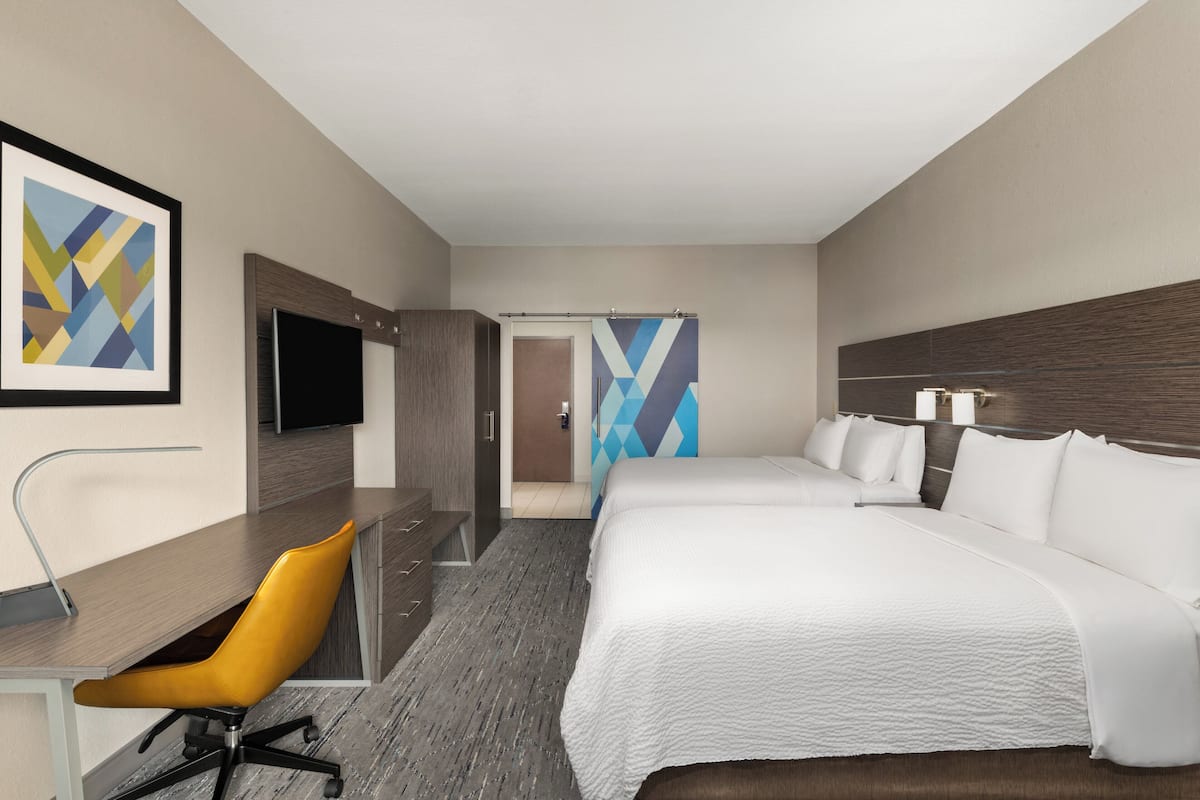 Une chambre d’hôtel comprenant un lit, un bureau avec une chaise, une télévision et une salle de bain avec douche.