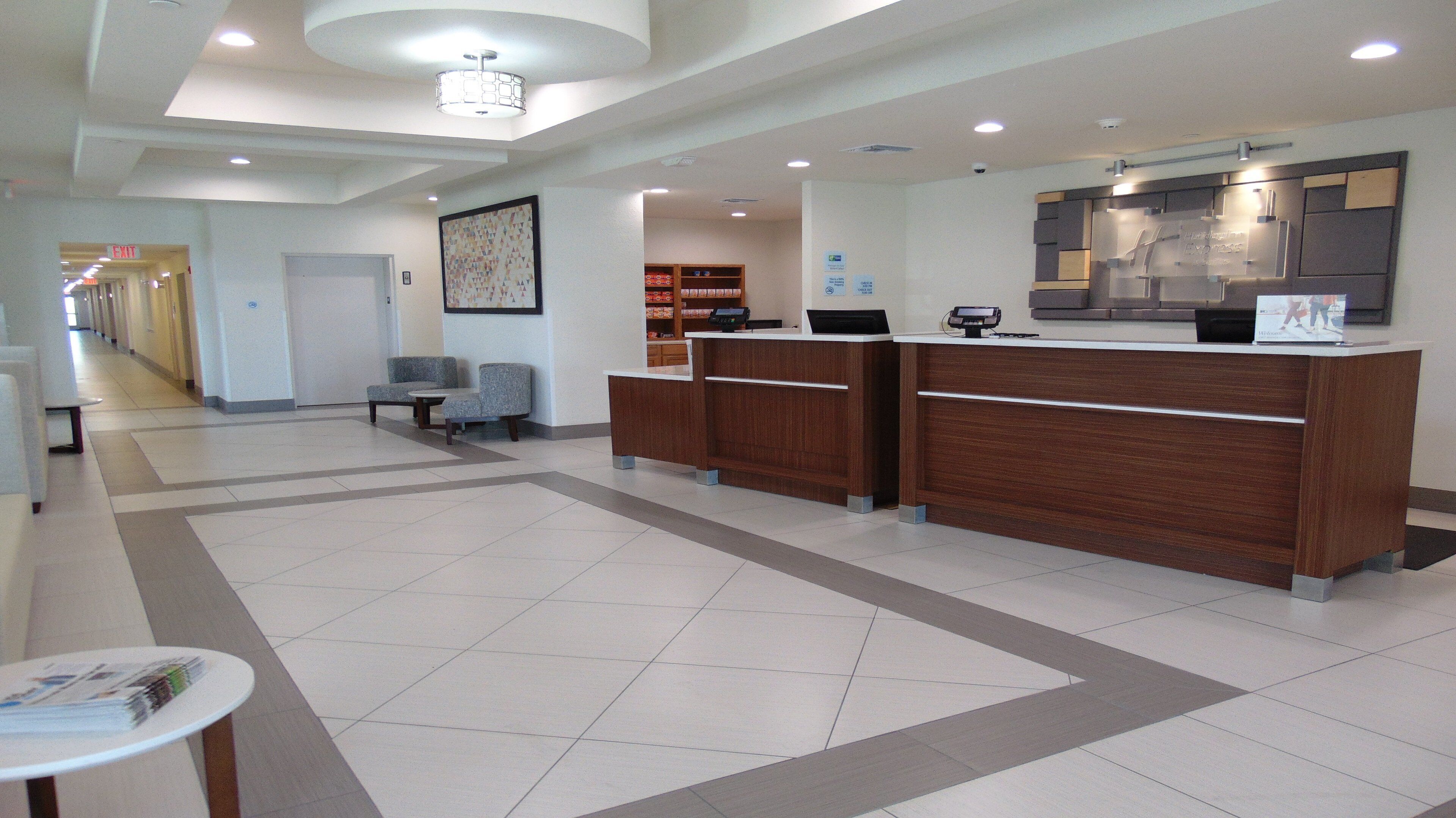 A reception area with a reception desk, seating, and a hallway leading to an exit.