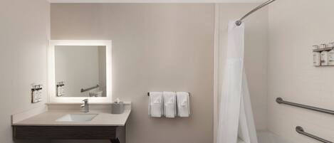 A modern bathroom with a sink, mirror, towel rack, and shower area.