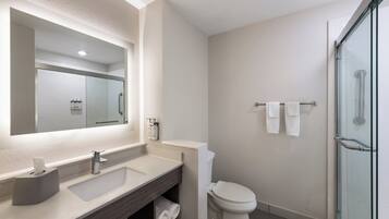 Un baño moderno con un espejo grande, un lavabo, un inodoro y una cabina de ducha de cristal.