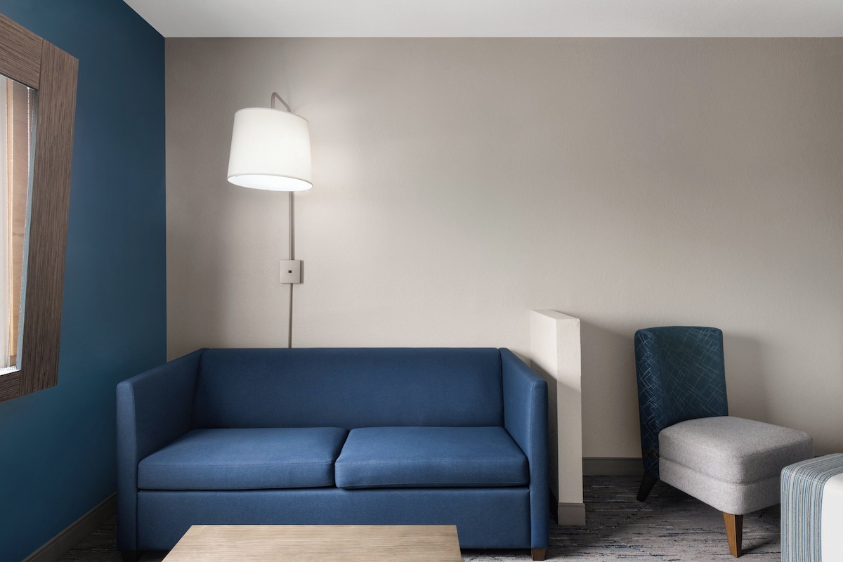 A modern living room with a blue sofa, a floor lamp, and a chair.
