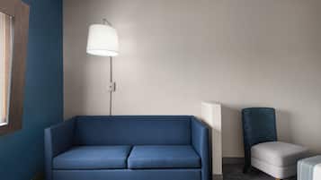Una sala de estar moderna con un sofá azul, una lámpara de pie y un sillón.