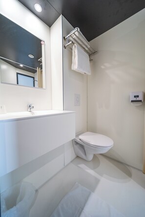 A modern bathroom with a white sink, mirror, and toilet.