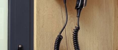 A black power strip with a coiled cable on a wooden surface.