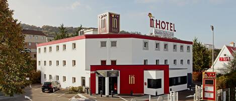 A hotel with a red and white facade, a visible entrance, and a sign indicating a lobby.