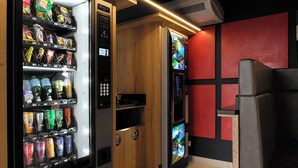 Een automaat met snacks en drankjes, een prullenbak en een container voor recycling.
