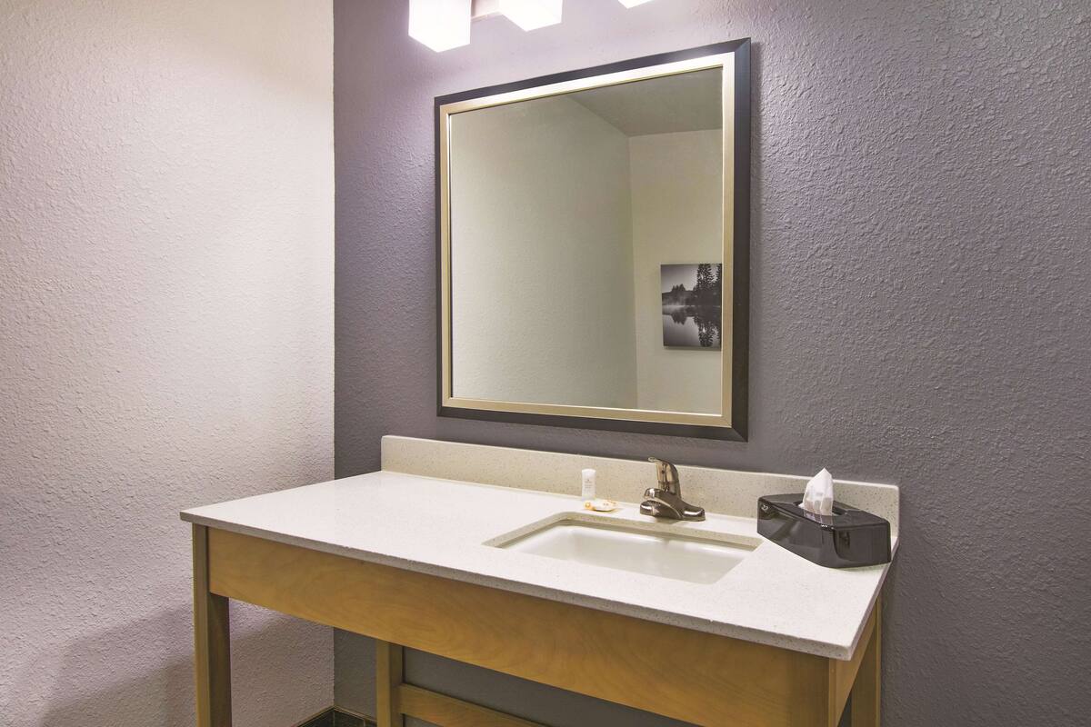 A bathroom with a white sink, a mirror, and a tissue box.