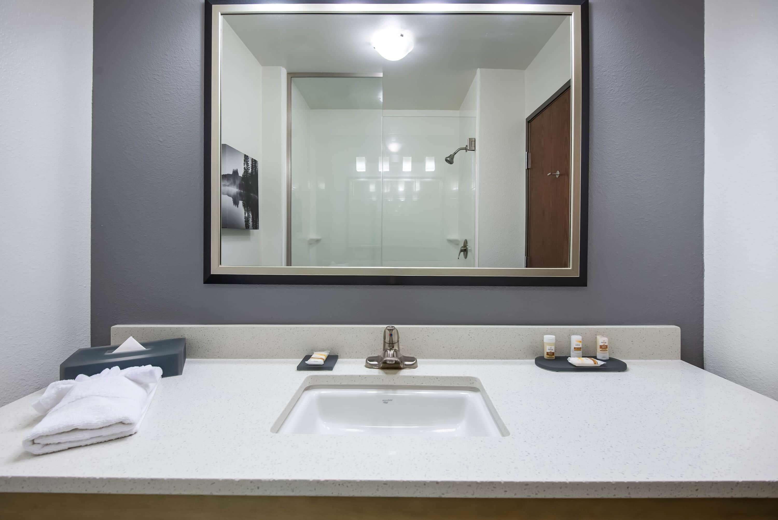 A bathroom with a white sink, a large mirror, and a towel on the counter.