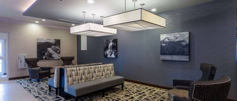 Un hall moderno con un sofá gris, alfombra estampada y lámparas contemporáneas.
