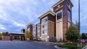 Un hôtel La Quinta au design moderne, caractérisé par une entrée imposante, de nombreuses fenêtres et un parking.