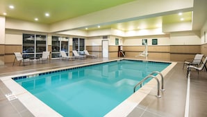Une piscine équipée de chaises longues et d’un panneau indiquant une limite de hauteur, soit entre 1,52 m et 1,68 m.