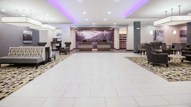 Un hall d’hôtel moderne comprenant un comptoir d’accueil, un espace salon et une grande fenêtre donnant sur un pont.
