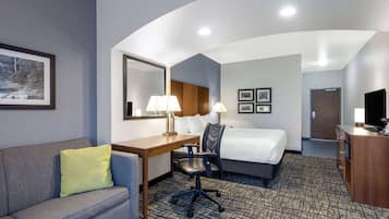 A hotel room with a bed, desk, chair, and a television.