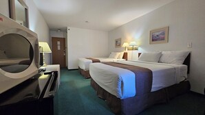 A hotel room with two beds, a TV, a desk, and a bathroom door.