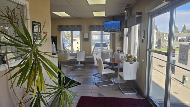 A restaurant with a TV, chairs, tables, and a plant.