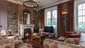 A living room with a fireplace, stone wall, and large windows with curtains.