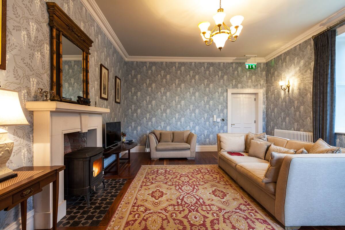 Una sala de estar acogedora con chimenea, un sofá y un tapete estampado.
