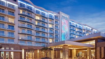 Experience the sleek, curved facade of Paséa Hotel & Spa, featuring a covered walkway and landscaped garden entrance.