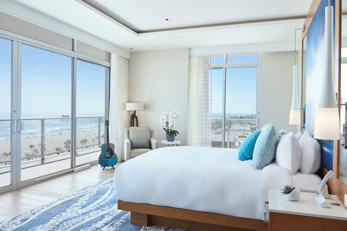 A spacious bedroom with a large bed, a view of the beach, and a balcony.