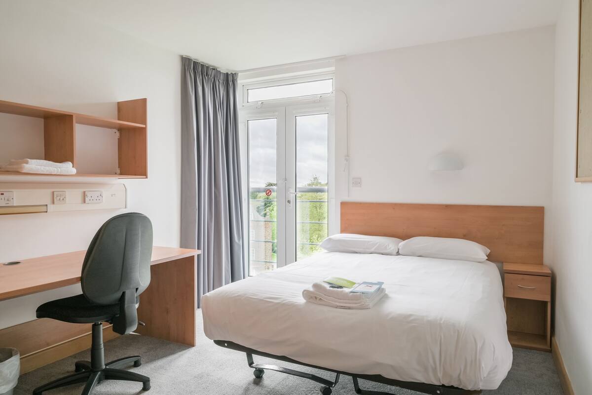 Une chambre d’hôtel avec un lit, un bureau et une chaise.