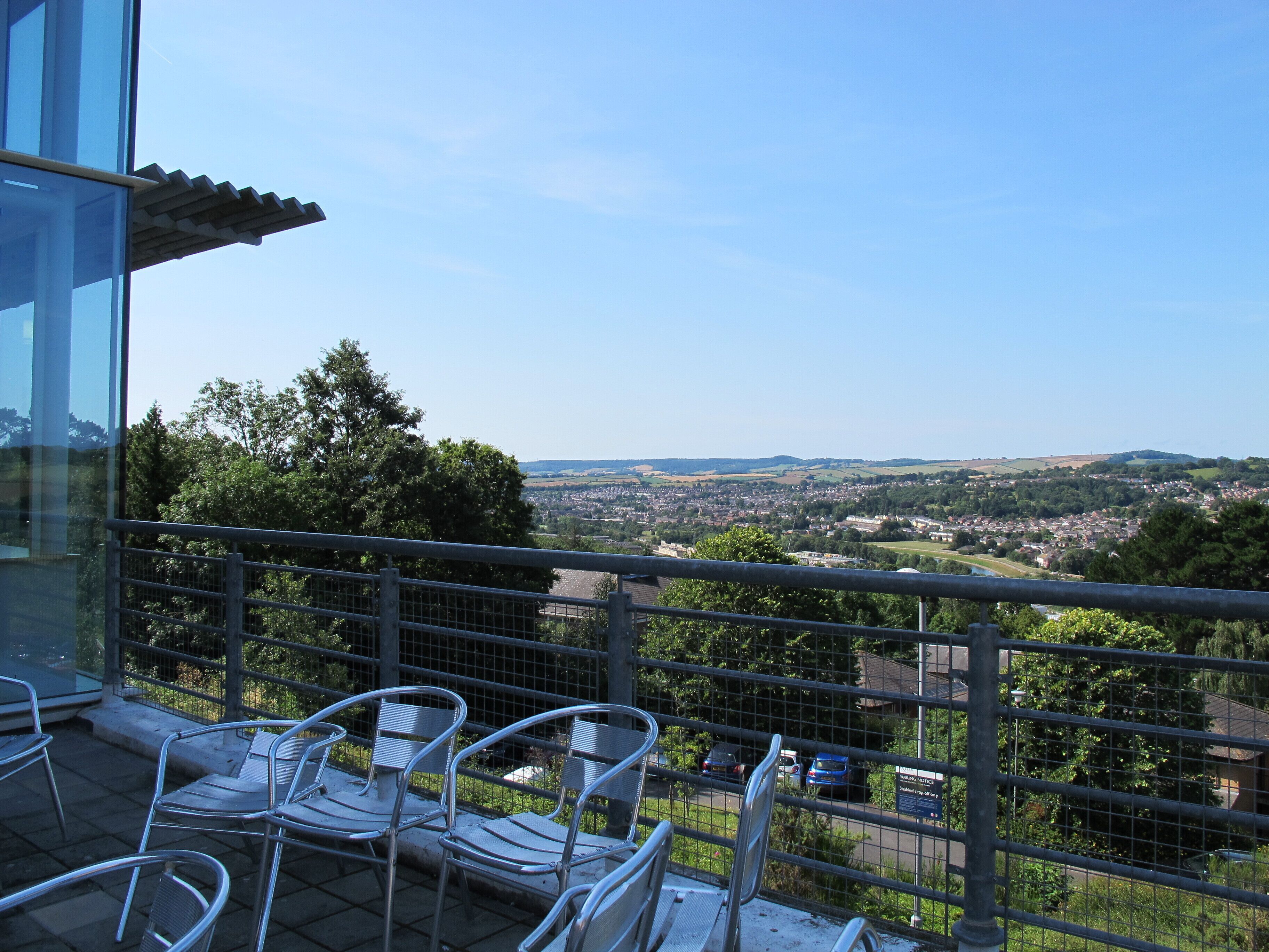 Un balcon avec des chaises en métal et une vue sur la ville et les collines.