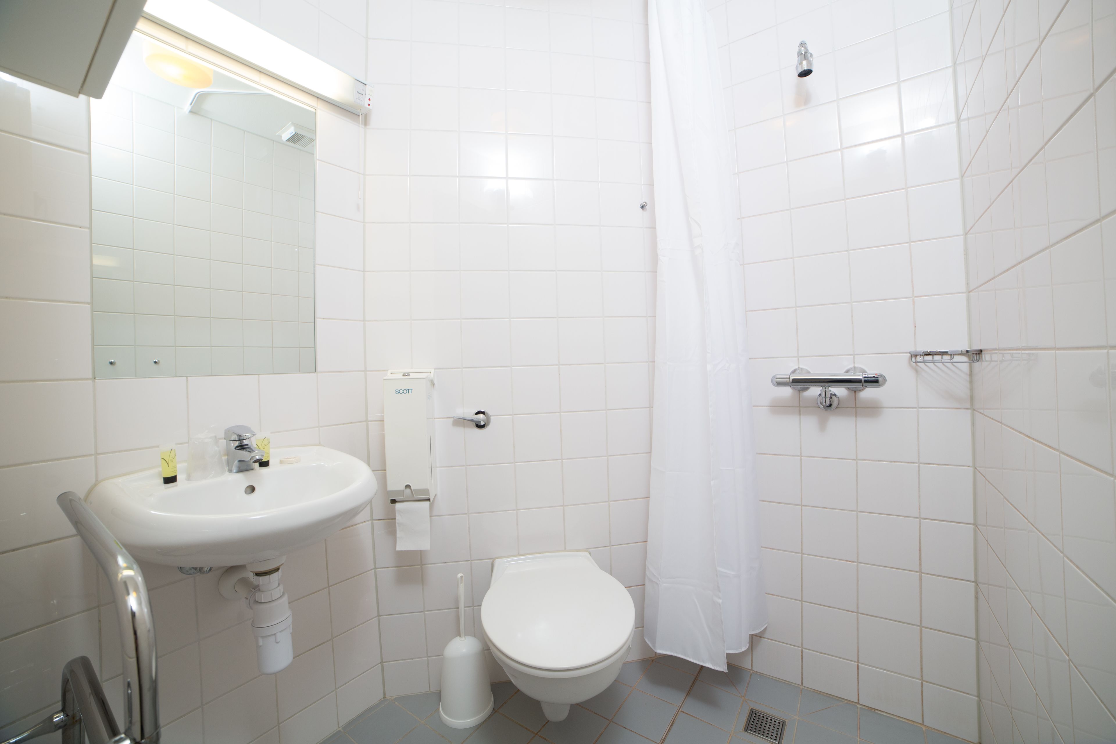 A bathroom with a white sink, toilet, and shower curtain.