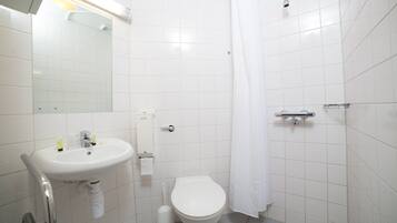 A bathroom with a white sink, toilet, and shower curtain.
