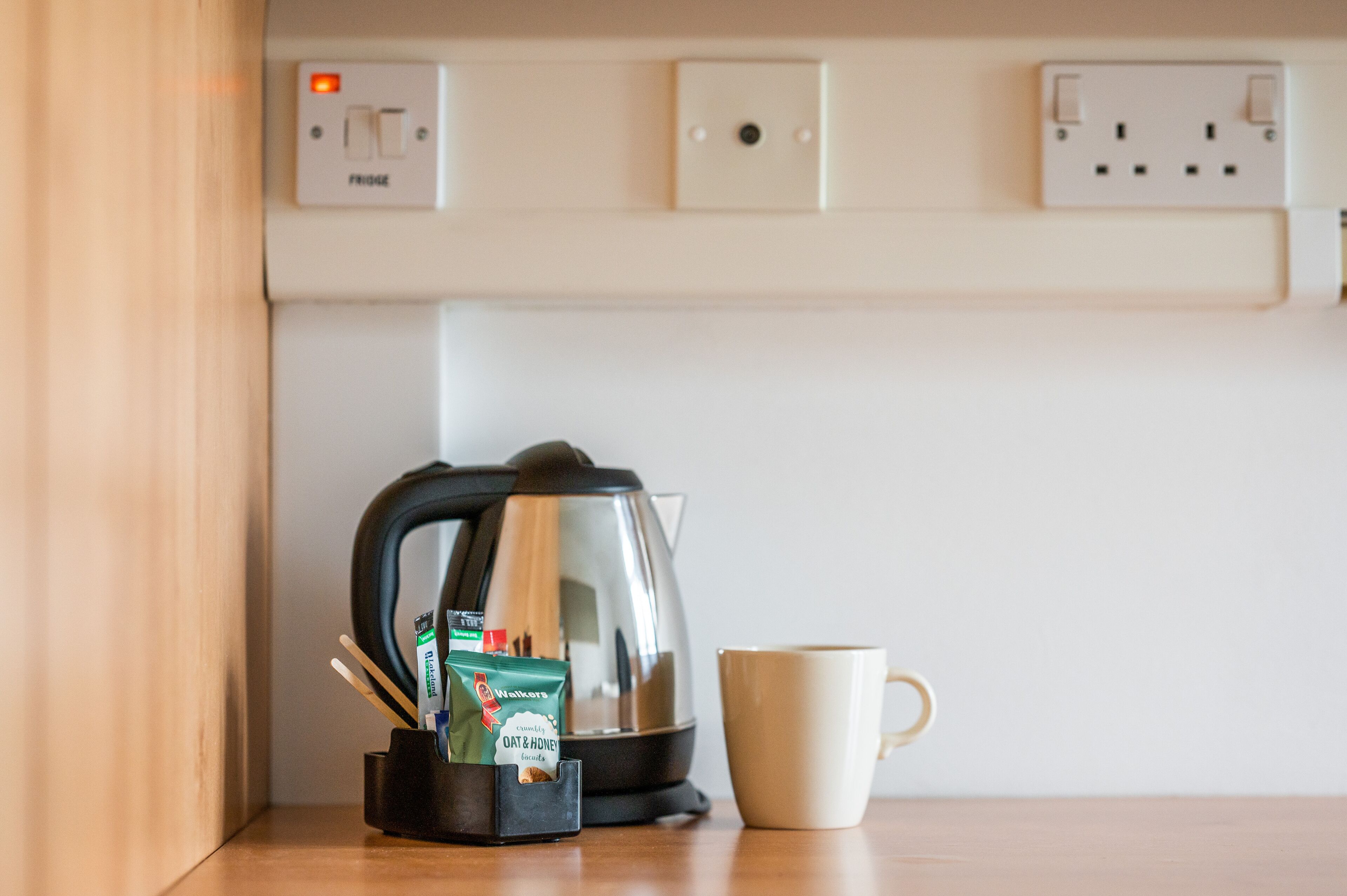 En køkkenbordplade med en kaffemaskine, en kop og en pakke kaffefløde.