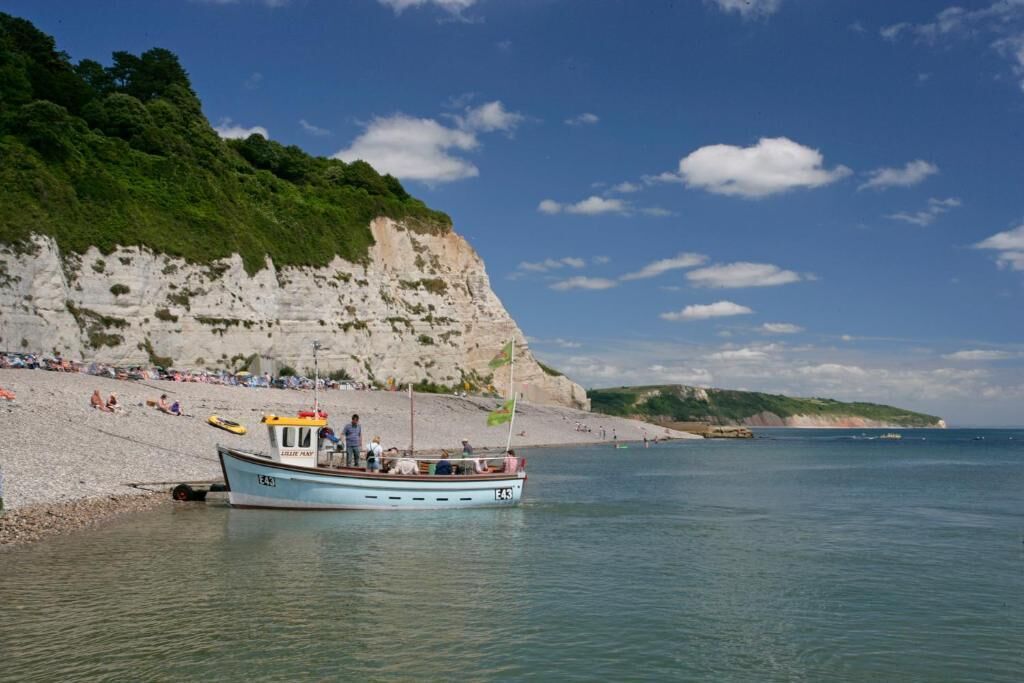 A boat docked at a beach with a rocky cliff in the background.