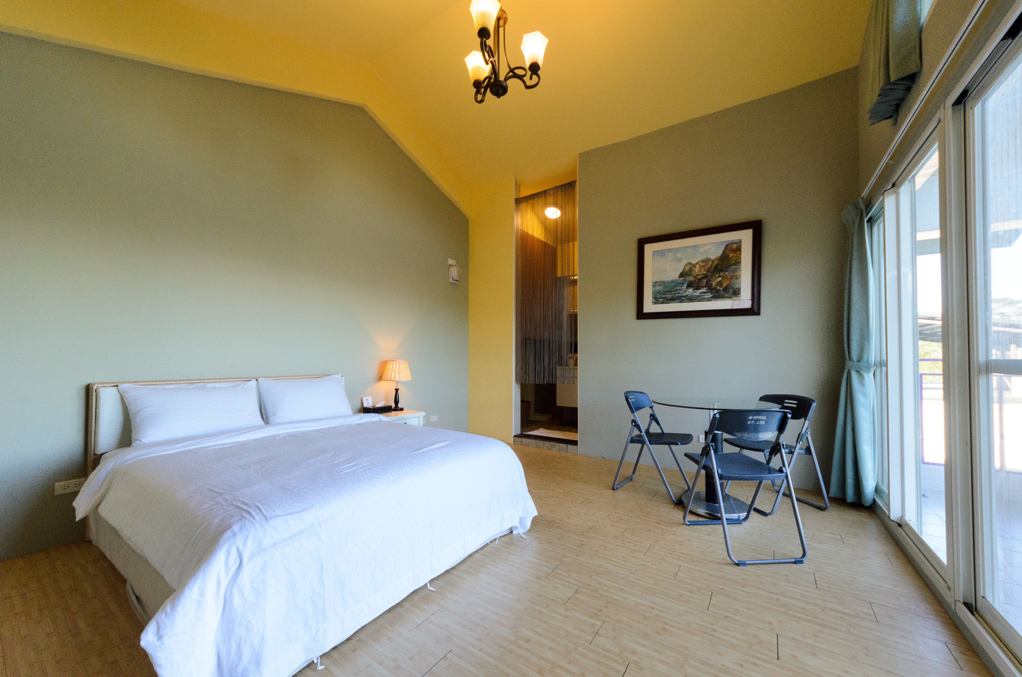 Habitación de hotel con una cama grande, un escritorio con sillas, un cuadro en la pared y vistas por la ventana.